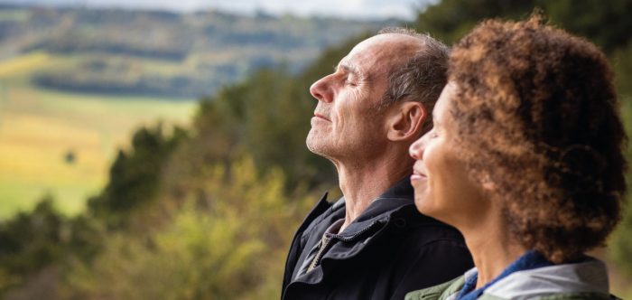 A couple with their eyes closed enjoying a peaceful landscape