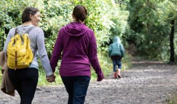 A couple holding hands and walking along a country path