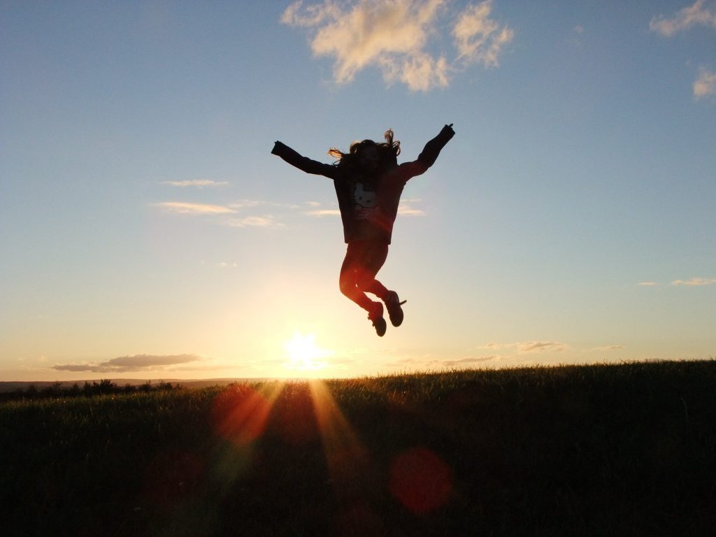 A small child jumping for joy in the sunset