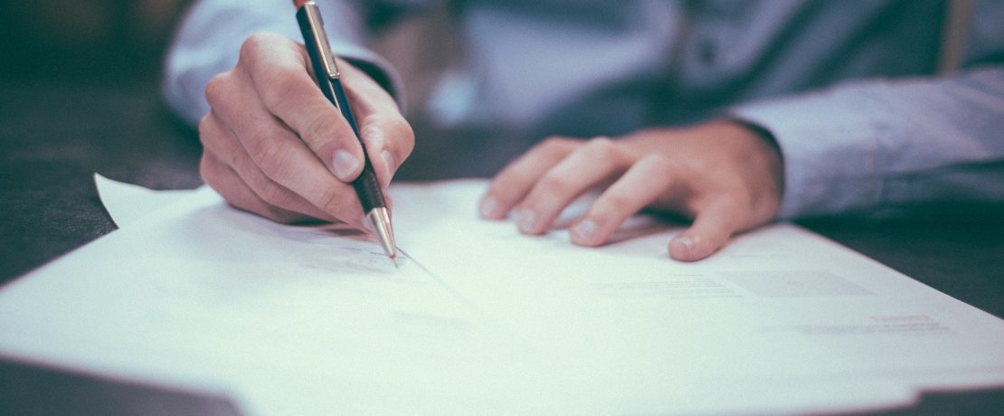 A close-up of a man signing a document