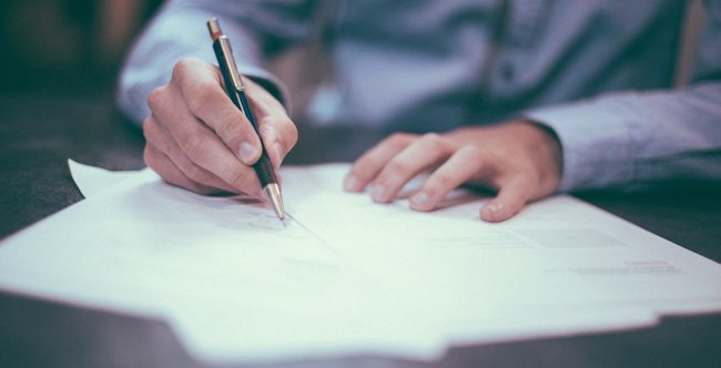 A close-up of a man signing a document