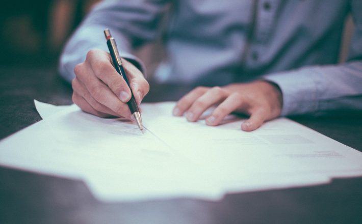 A close-up of a man signing a document