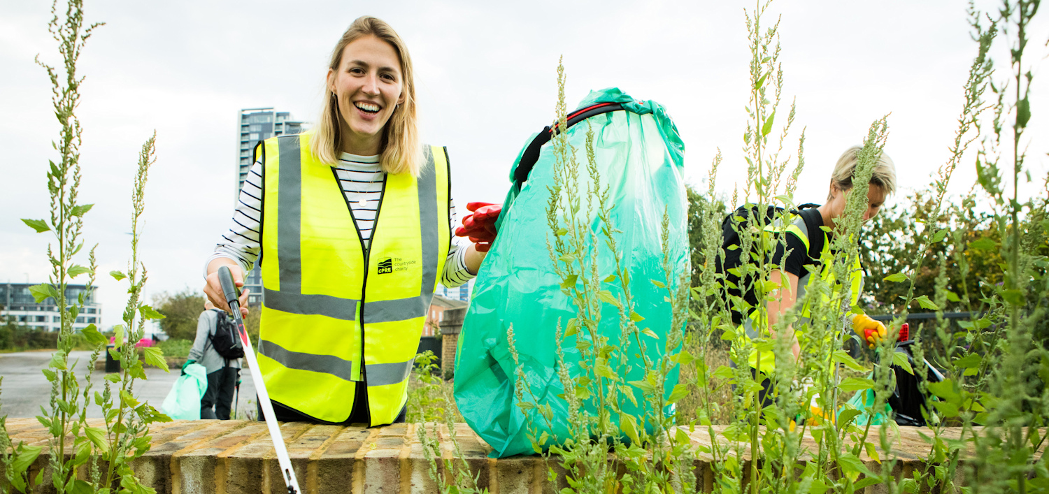 Happy woman picking litter with recycling bag