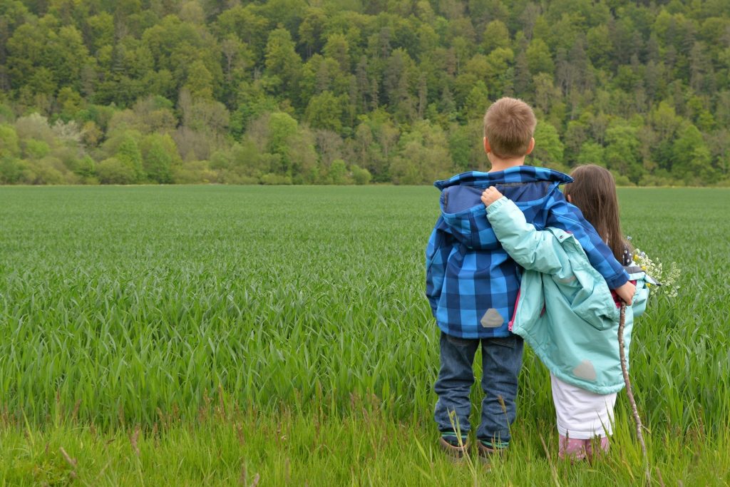 Children in the countryside looking across a field of crops