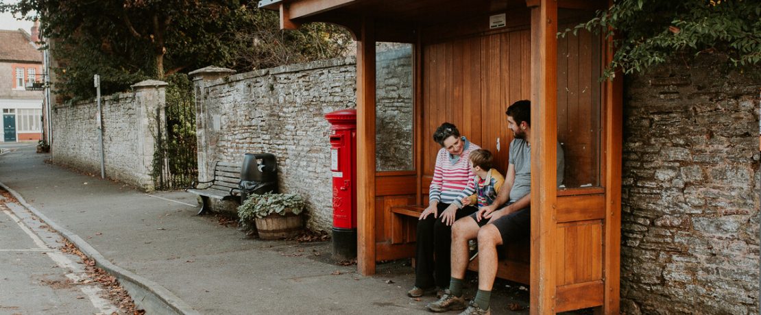 Family sat a rural bus stop waiting for a local bus