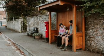 Family sat a rural bus stop waiting for a local bus