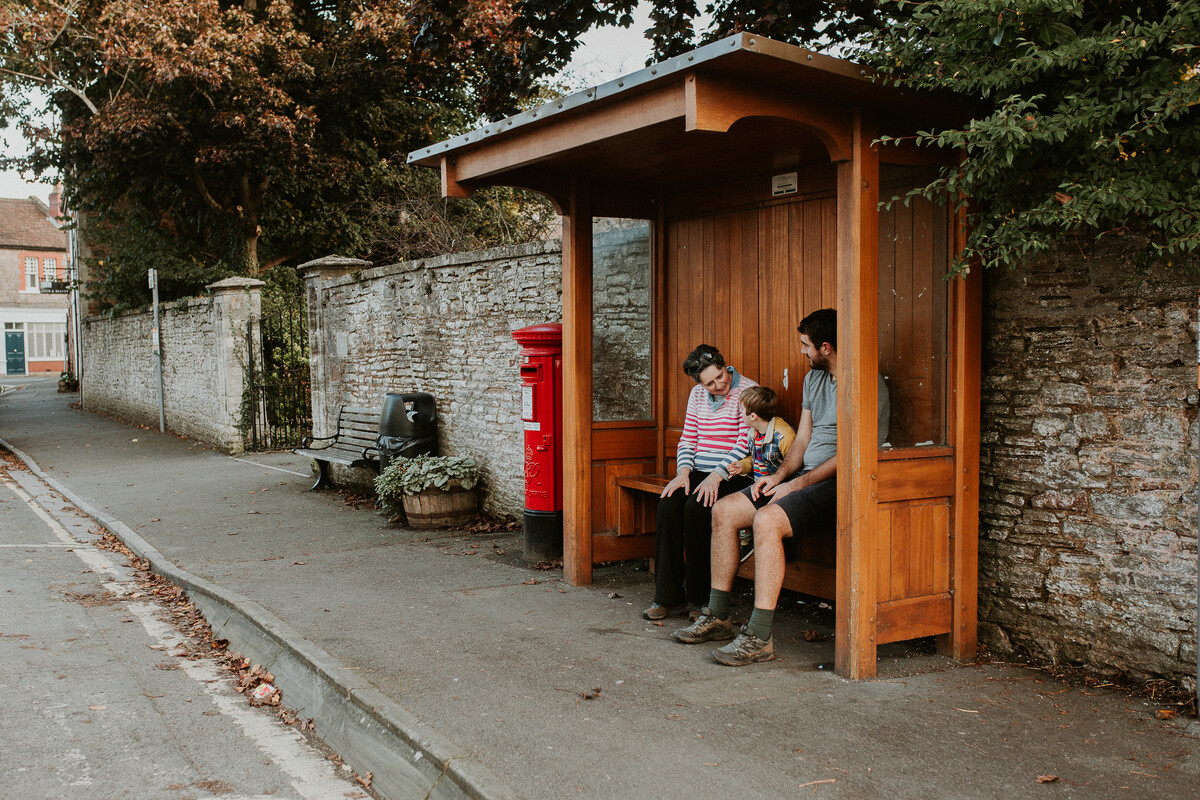 Family sat a rural bus stop waiting for a local bus