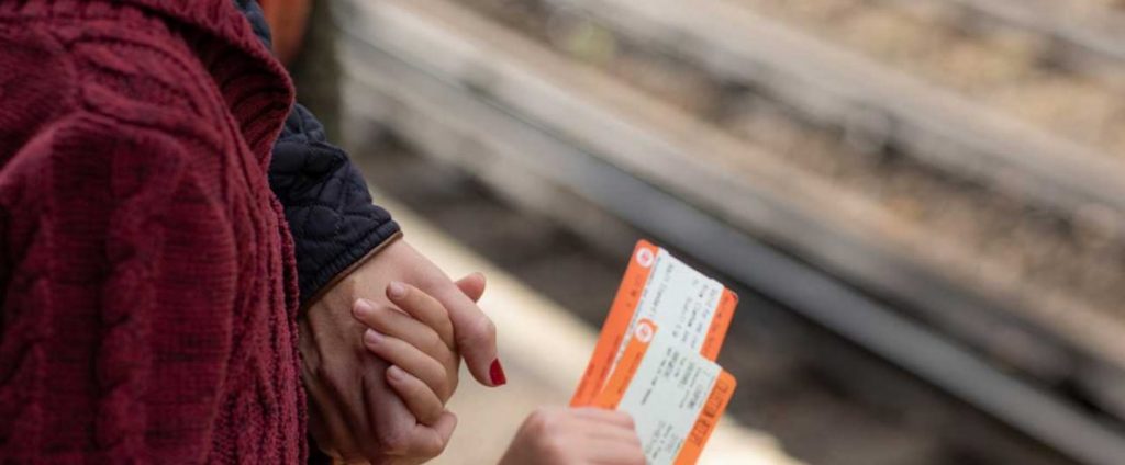 A woman and child holding hands and clutching rail tickets