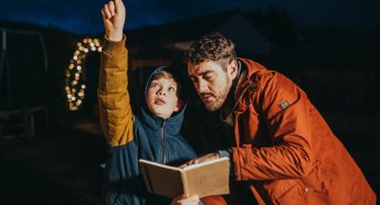 Dad and son counting stars in a garden in the night