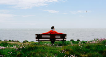 Man sitting on a coastal bench looking at the sea