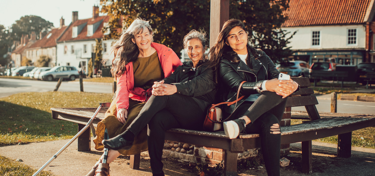 Three women sitting on a village bench in North Norfolk