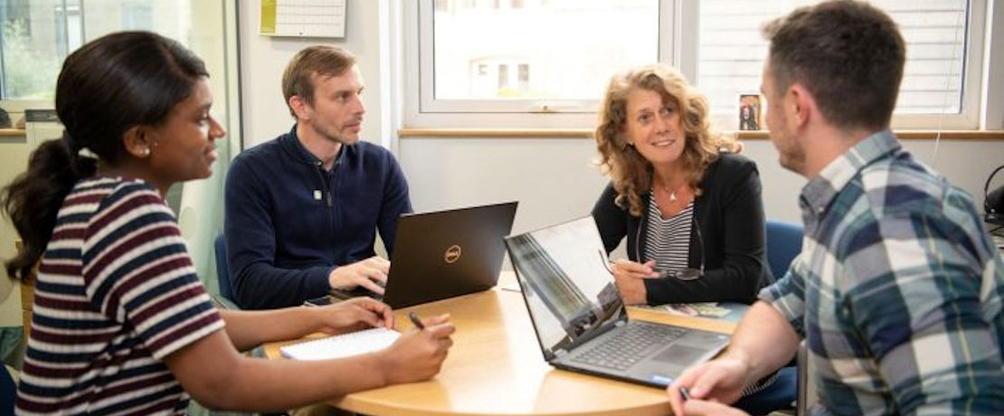 A group of four people sat around a table in a meeting