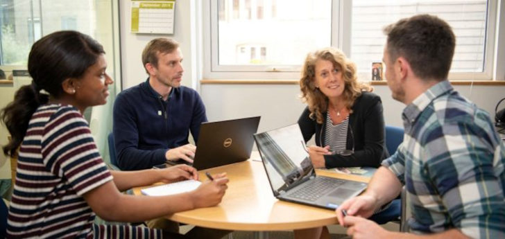 A group of four people sat around a table in a meeting