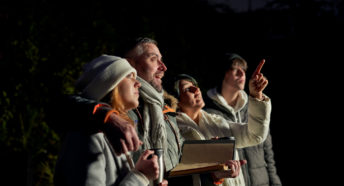 Family looking up at the night sky while while mother points