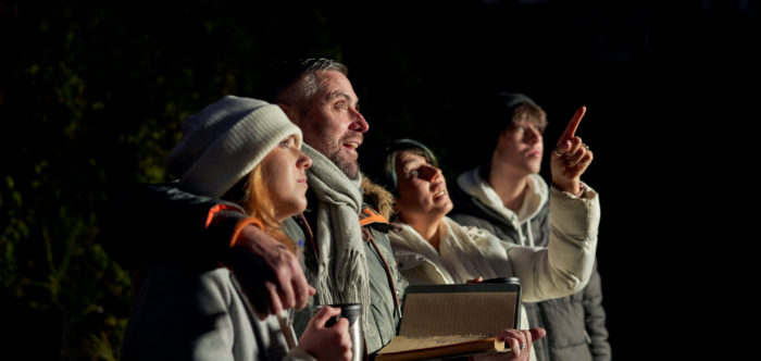 Family looking up at the night sky while while mother points