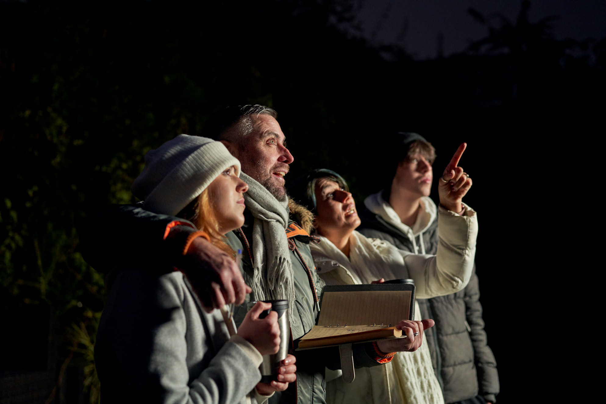 Family looking up at the night sky while while mother points