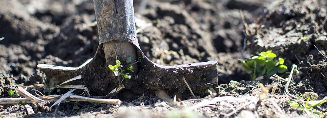 A spade digging in soil
