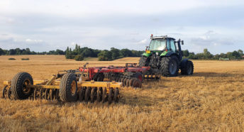 A tractor towing farm equipment on a recently harvested field