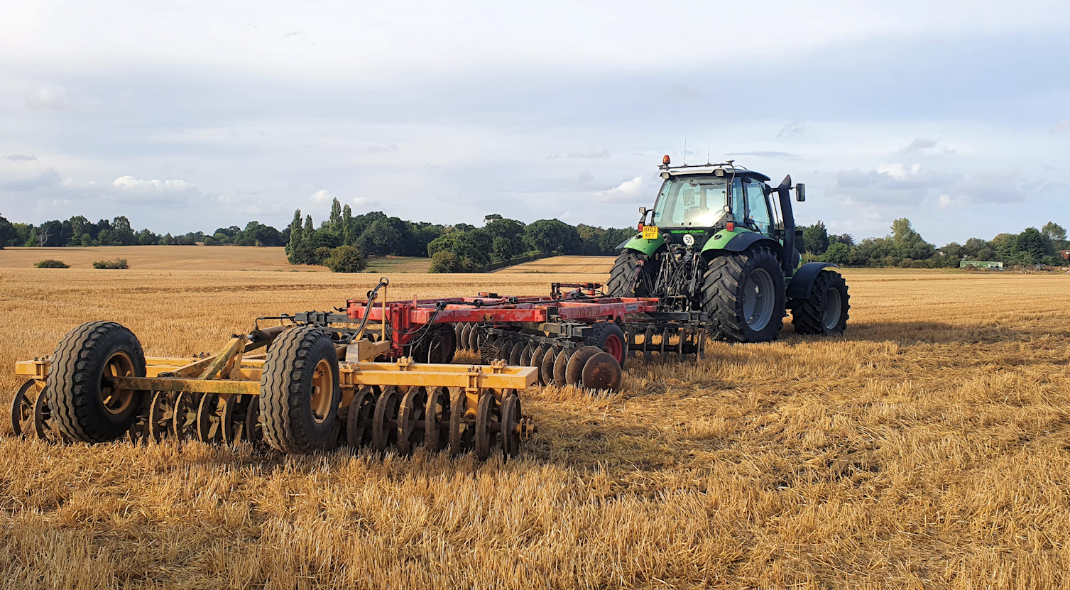 A tractor towing farm equipment on a recently harvested field