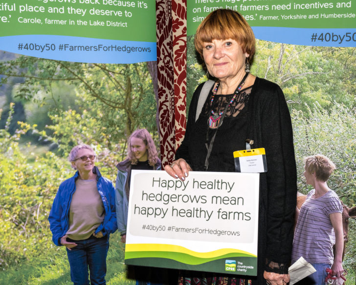 CPRE Norfolk's Sandra Walmsley holding a sign saying "Happy healthy hedgerows mean happy healthy farms"