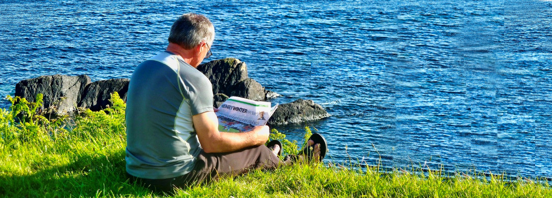Man reading a newspaper by the sea