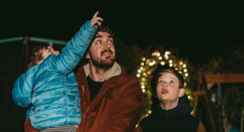 Father and children looking up at the night sky counting stars