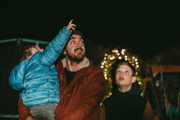Father and children looking up at the night sky counting stars