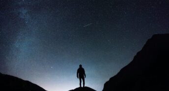 A solo figure silhouetted against a night sky filled with stars