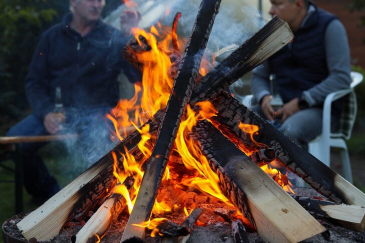 Close up of a bonfire with friends sitting in the background