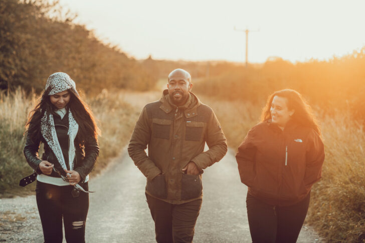 Three people walking into camera on a Norfolk lane at sunset