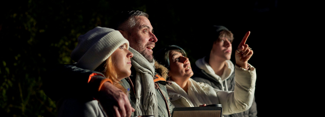 Family looking up at the night sky while while mother points