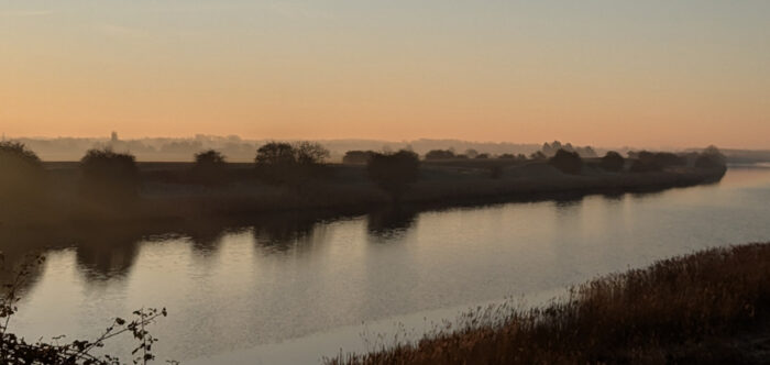 A countryside horizon showing a west Norfolk river at dusk with the open landscape beyond.