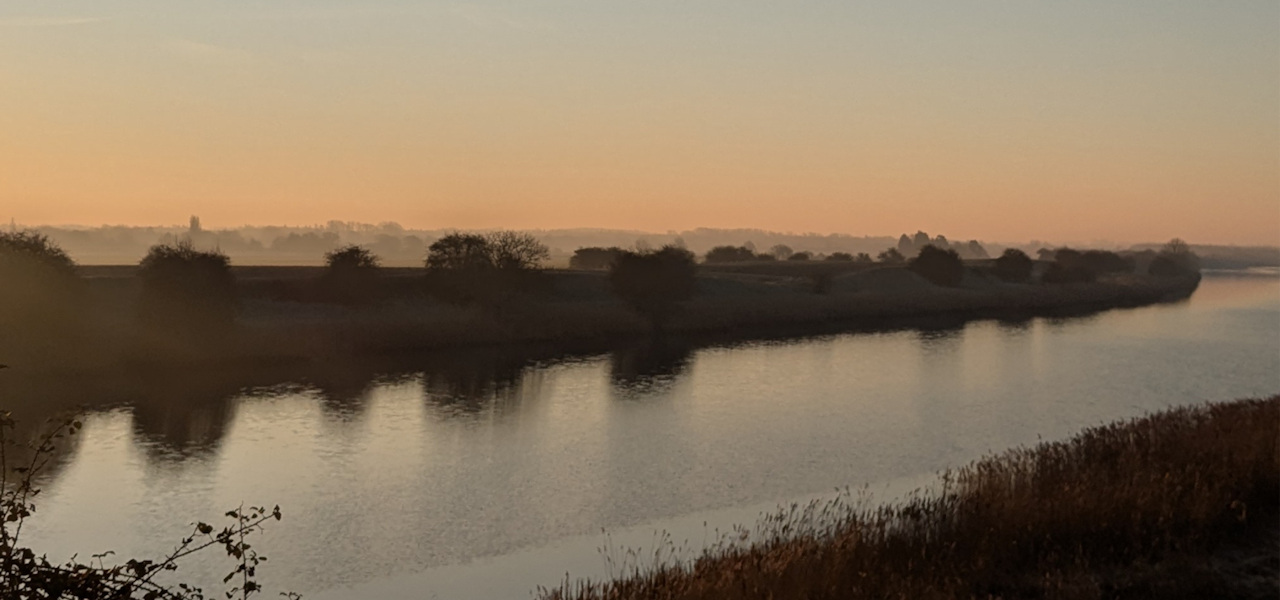 A countryside horizon showing a west Norfolk river at dusk with the open landscape beyond.