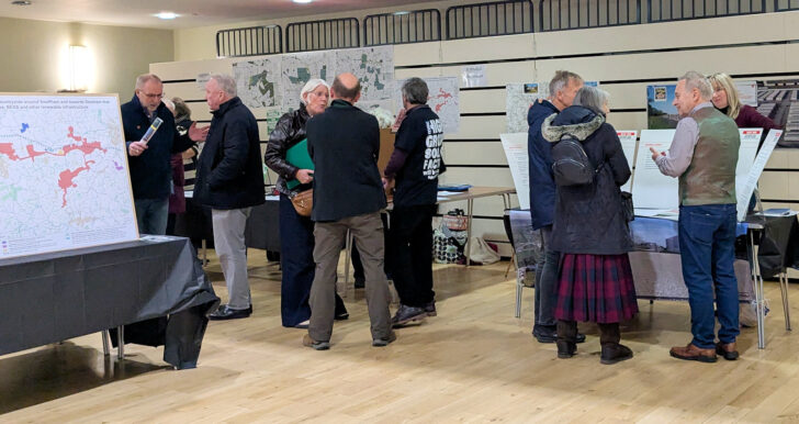 Large groups of people reading display boards and talking with exhibitors at the Getting Solar OFF the Land exhibition