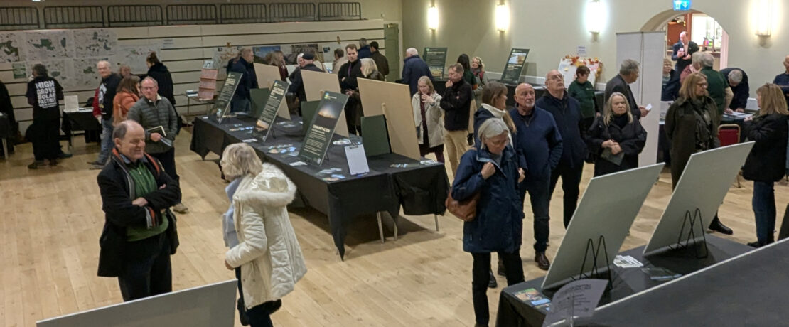 Large groups of people reading display boards and talking with exhibitors at the Getting Solar OFF the Land exhibition
