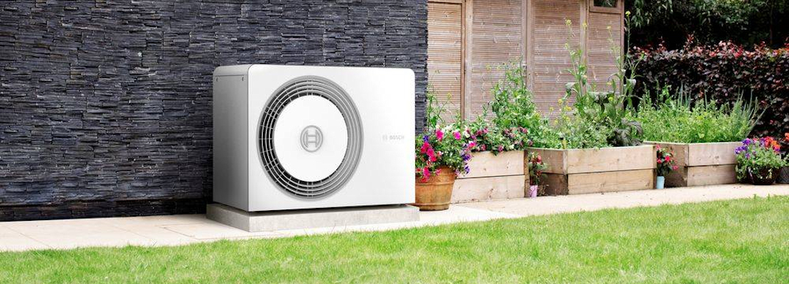 An air source heat pump located on an external wall in a garden