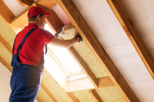 A man applying insulation to a wall in a loft space
