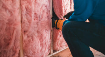 A worker insulating a wall with fibreglass insulation