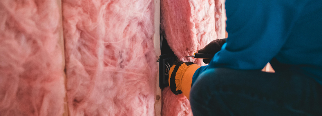 A worker insulating a wall with fibreglass insulation