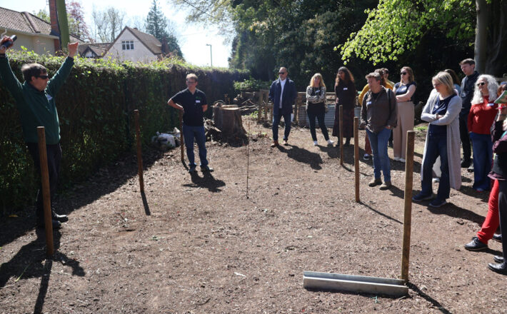 A group of people stand in nature listening to Daniel Salliss (BFL) giving a presentation on biodiversity