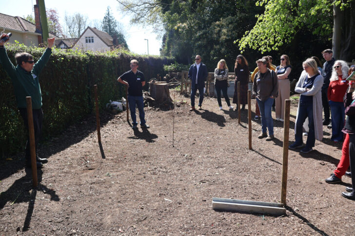 A group of people stand in nature listening to Daniel Salliss (BFL) giving a presentation on biodiversity