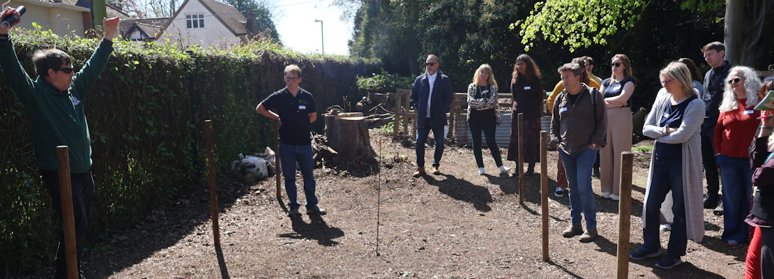 A group of people stand in nature listening to Daniel Salliss (BFL) giving a presentation on biodiversity