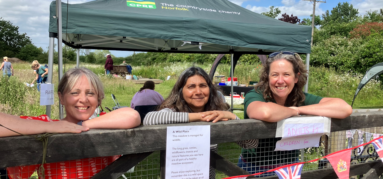 Three CPRE volunteers leaning on the entrance gate to Martha's Meadow
