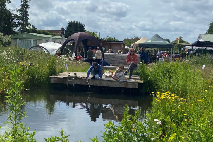 Children pond-dipping at Martha's Meadow with the stalls in the background