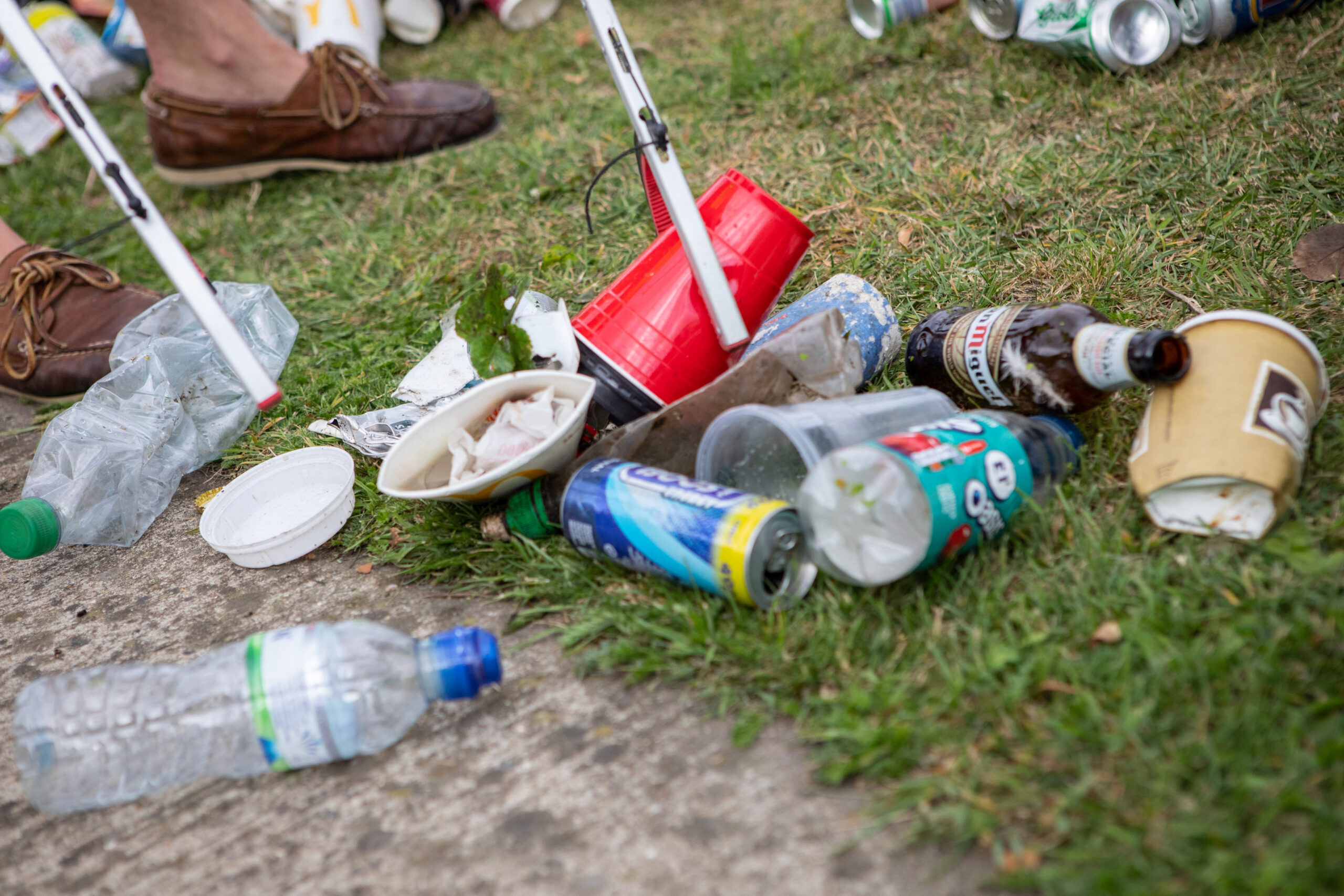Close-up of a grabber being used to pick up discarded litter from a grassed area.