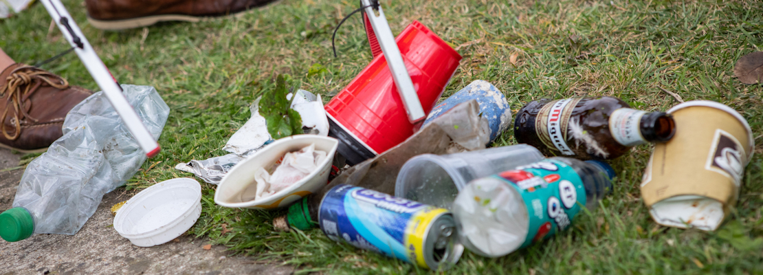 Close-up of a grabber being used to pick up discarded litter from a grassed area.