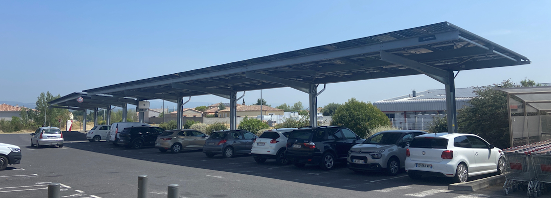 Solar panels mounted above the car park spaces at a supermarket in Alzonne, France